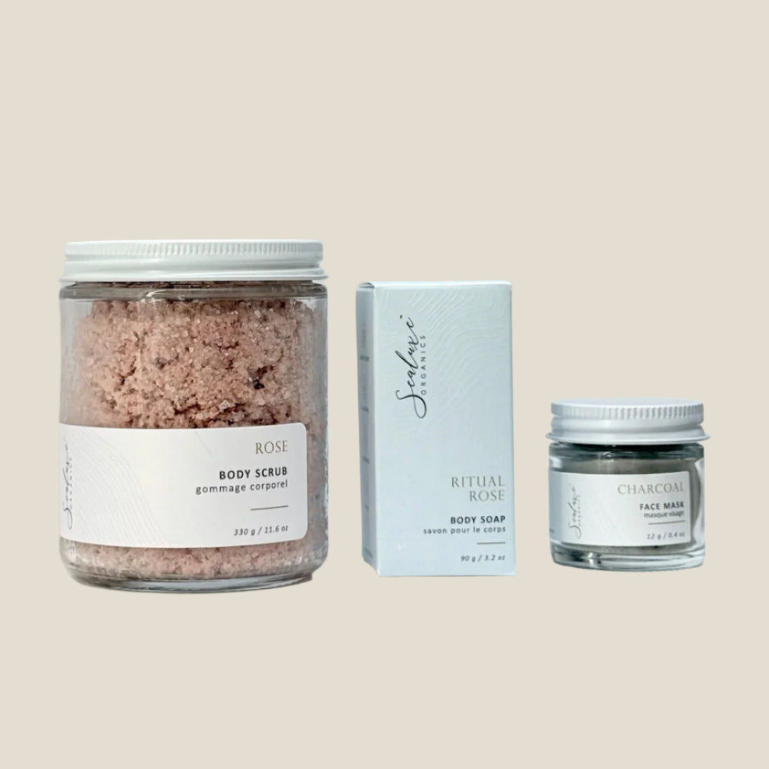 Three skincare products including a jar of body scrub, a box of soap, and a jar of face mask on a white background.