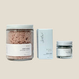 Three skincare products including a jar of body scrub, a box of soap, and a jar of face mask on a white background.