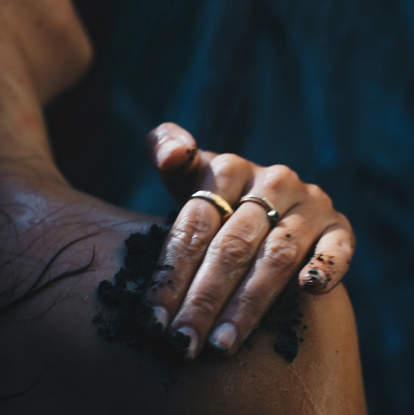 Using Sealuxe's seaweed and coffee scrub in shower on shoulder and neck.