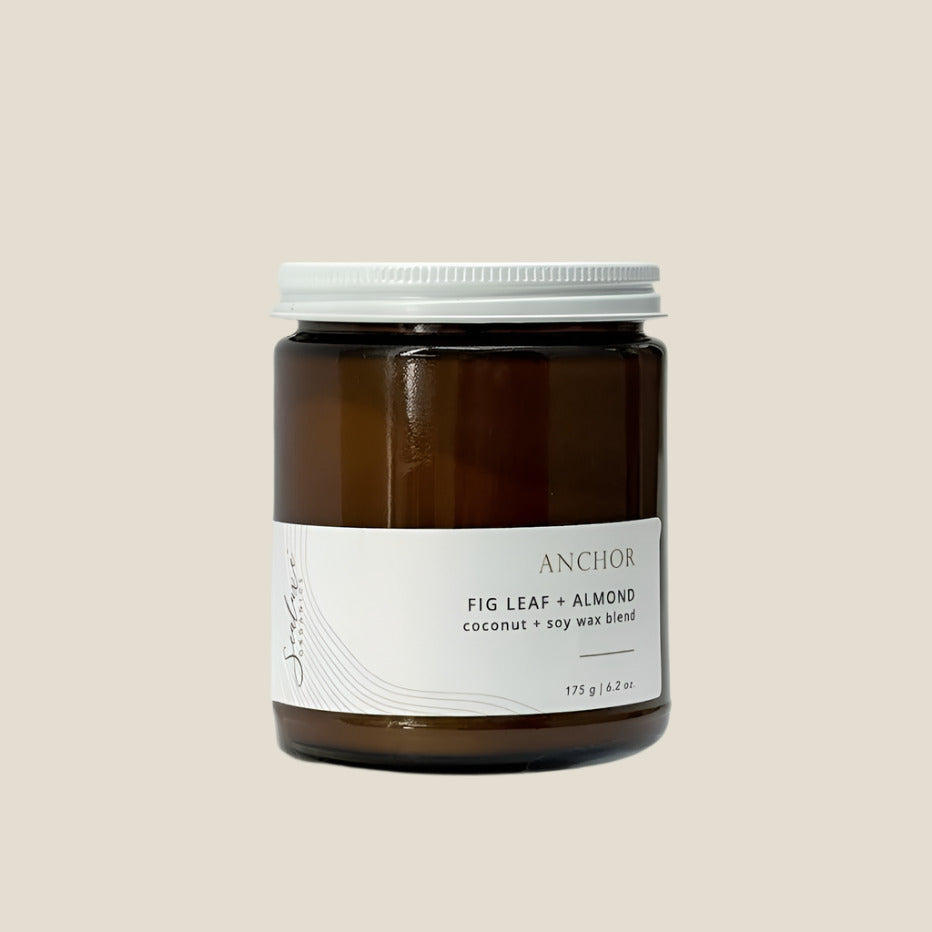 Brown candle jar with white lid and label on a light gray background