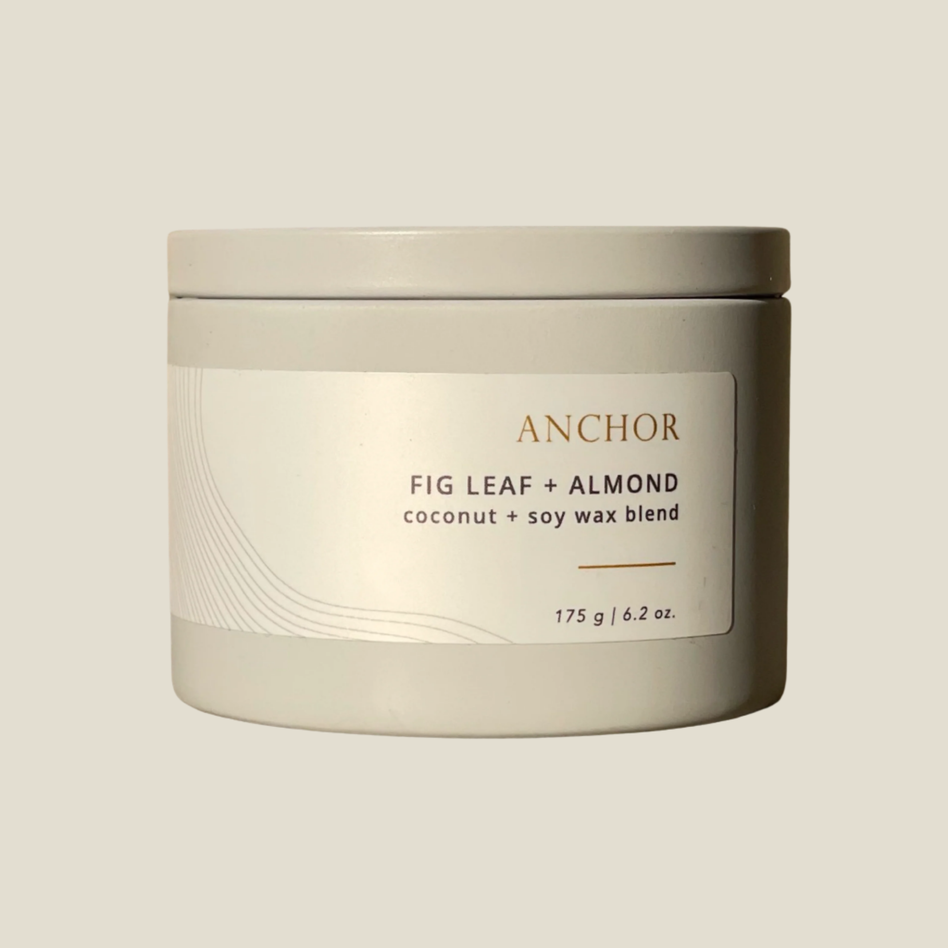 A metal tin container with a lid, labeled 'Anchor Fig Leaf + Almond', indicating a coconut soy wax blend candle.
