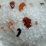 Close-up of white salt and rose salt and a black object on top