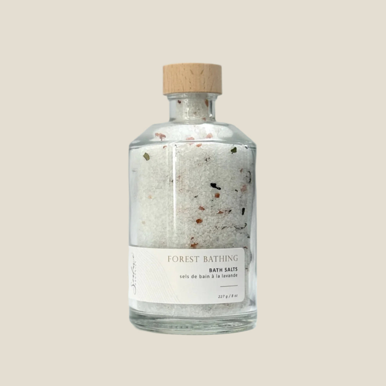 Bottle of 'Forest Bathing' bath salts with a wooden cap on a light gray background