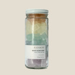 Glass jar with rainbow-colored beach glass soap on a beige background