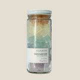 Glass jar with rainbow-colored beach glass soap on a beige background