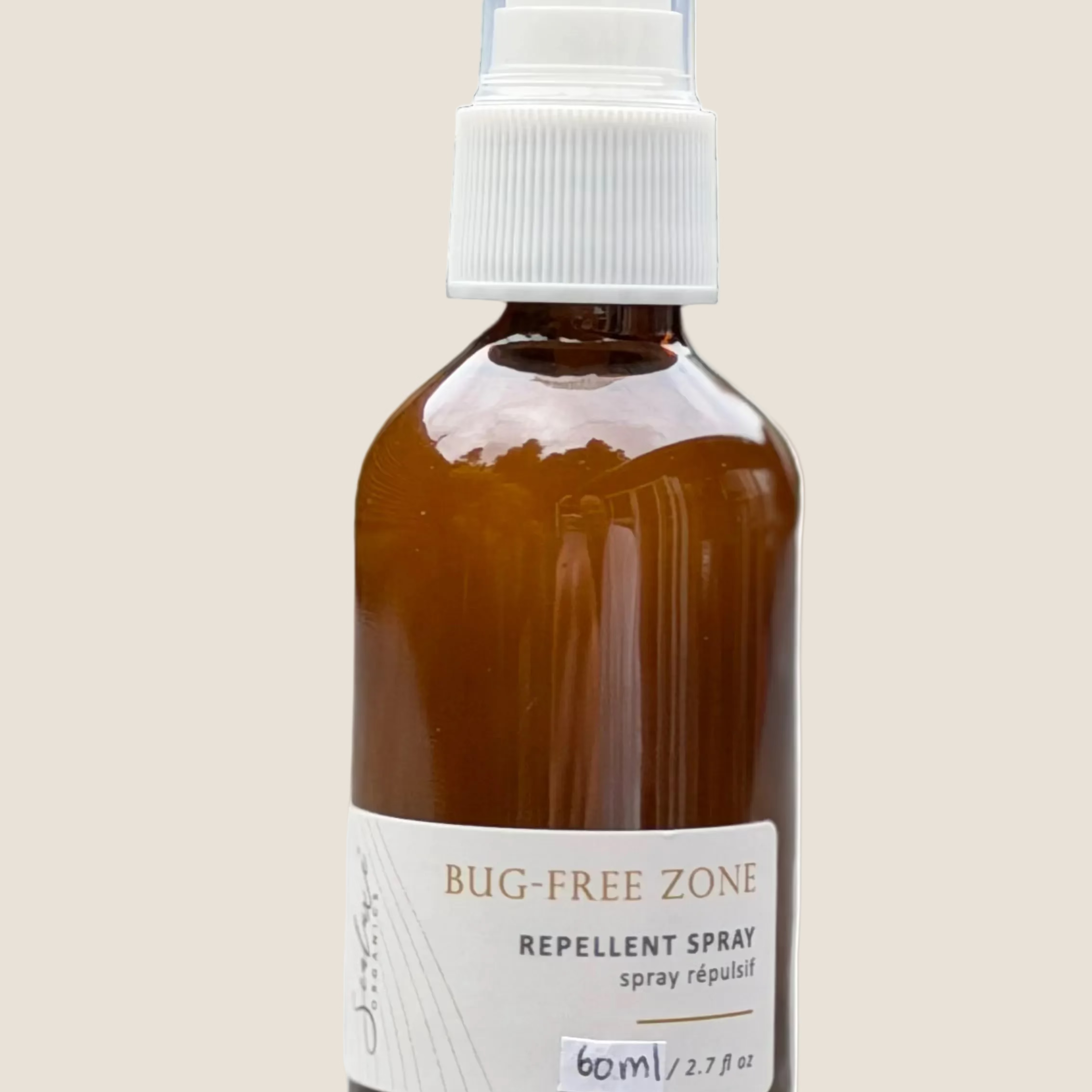 Brown spray bottle labeled 'Bug-Free Zone' on a light surface with a blurred green background
