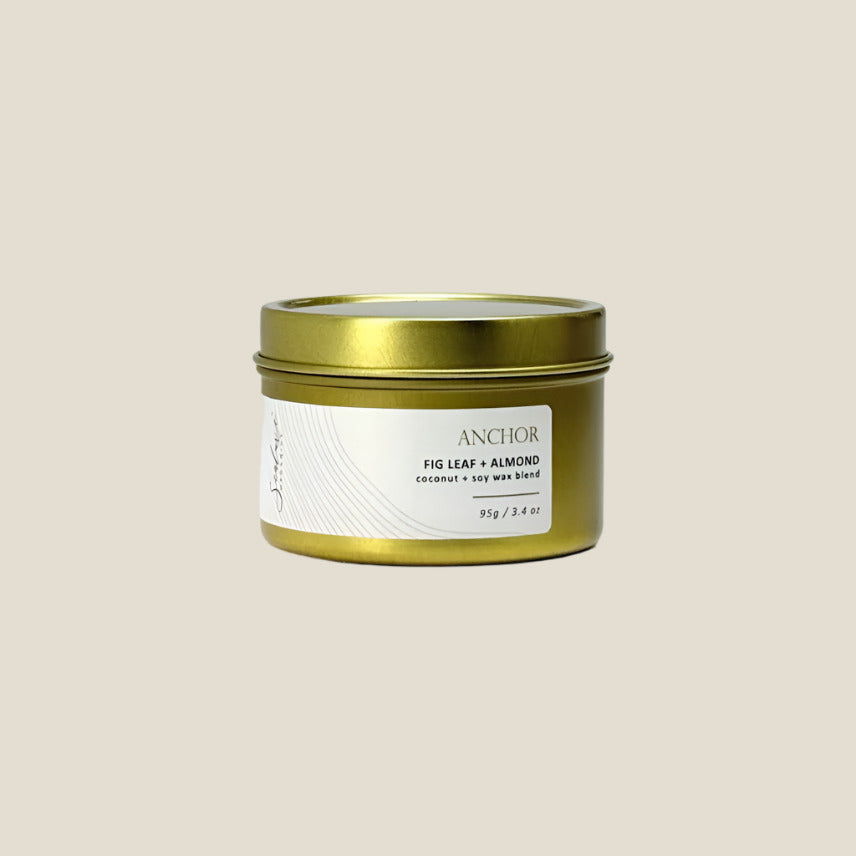 Gold candle tin with a white label on a light gray background