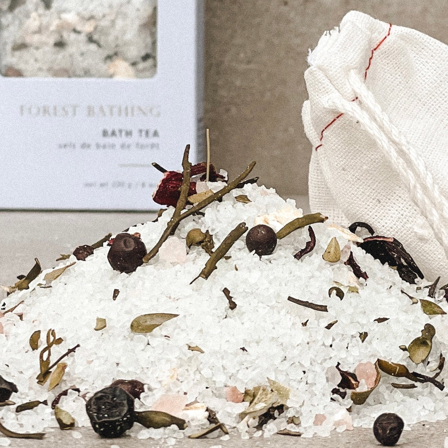 a pile of sea salts and seaweed with botanicals and a cloth bag with a blurred rectangle box in the background with the Sealuxe logo