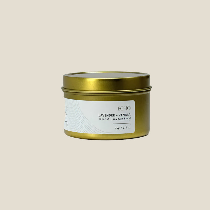 Candle tin with gold lid and white label on a light gray background