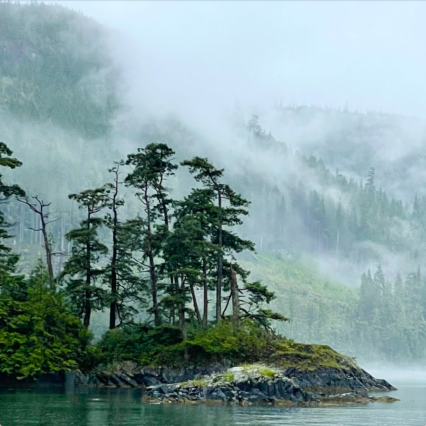 Island in a lake surrounded by misty mountains