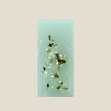 Green soap bar with embedded seaweed on a white background