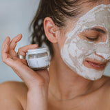 Woman with Sealuxe Alabaster clay face mask applied, smiling with eyes closed in natural light — natural face mask in use