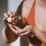 Hands applying Sealuxe Rose Body Oil to skin