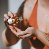 Hands applying Sealuxe Rose Body Oil to skin