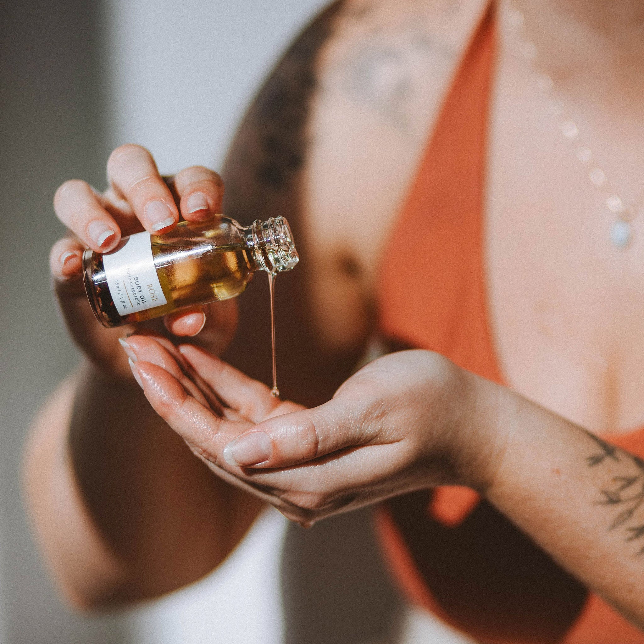 Hands applying Sealuxe Rose Body Oil to skin