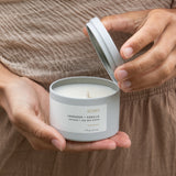 Hand holding an open Sealuxe Echo candle jar with the lid off