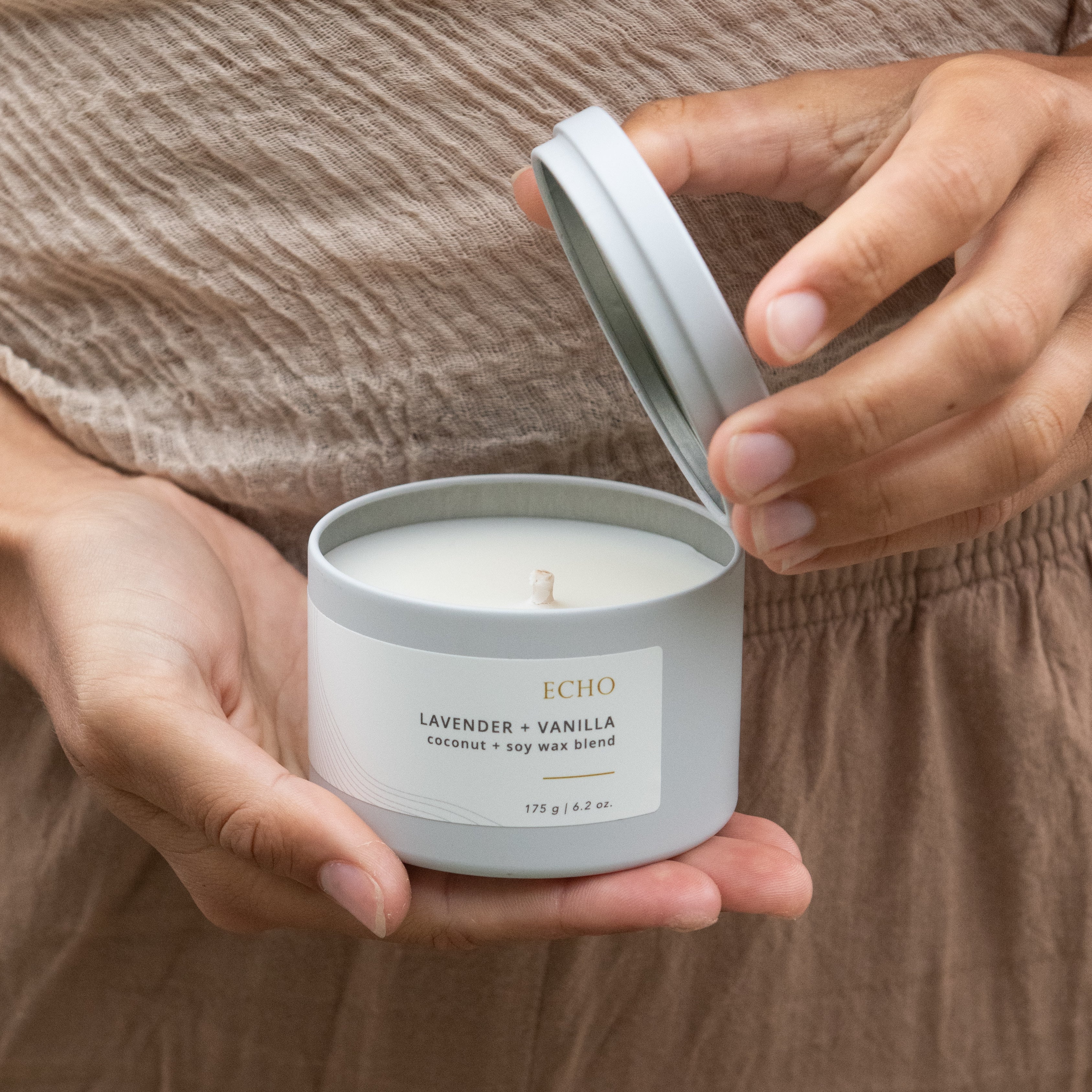 Hand holding an open Sealuxe Echo candle jar with the lid off