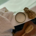 Sealuxe gold tin candle resting on the edge of a bathtub