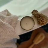 Sealuxe gold tin candle resting on the edge of a bathtub