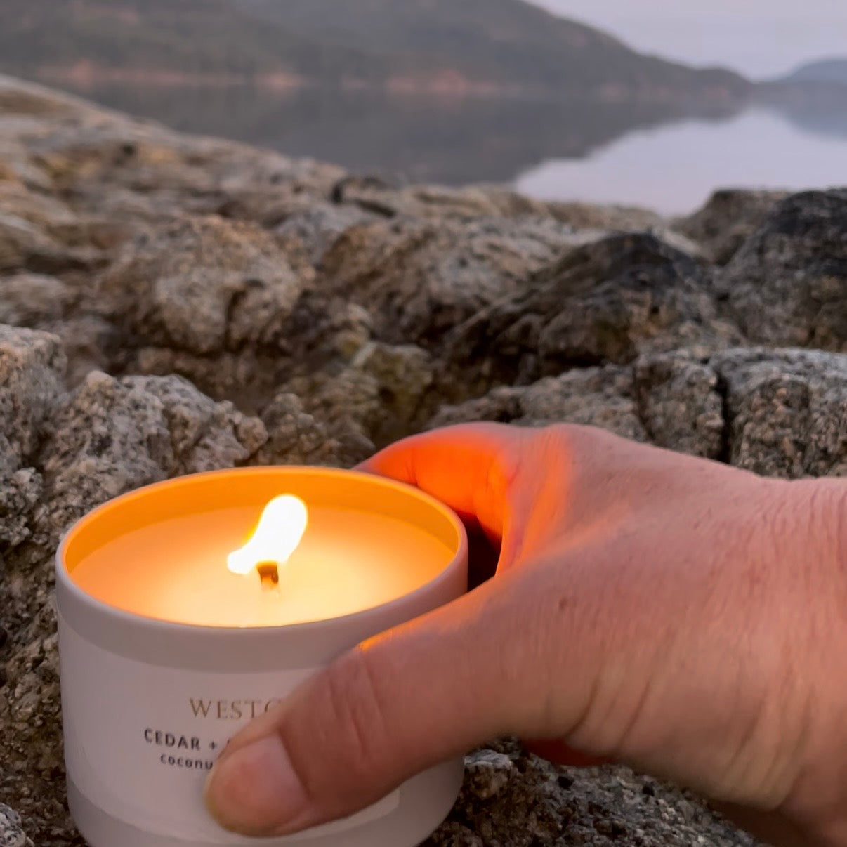 Hands holding a lit Sealuxe candle jar