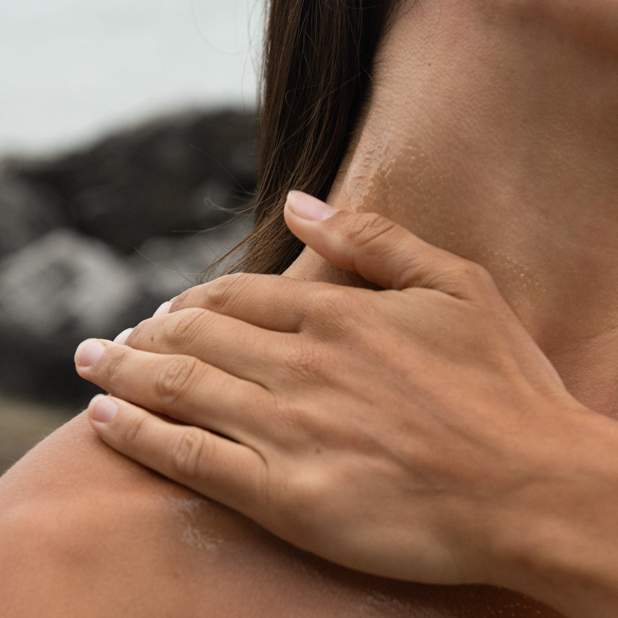 Close-up of hands massaging Sealuxe body oil into neck and shoulder skin — hydrating body oil in use