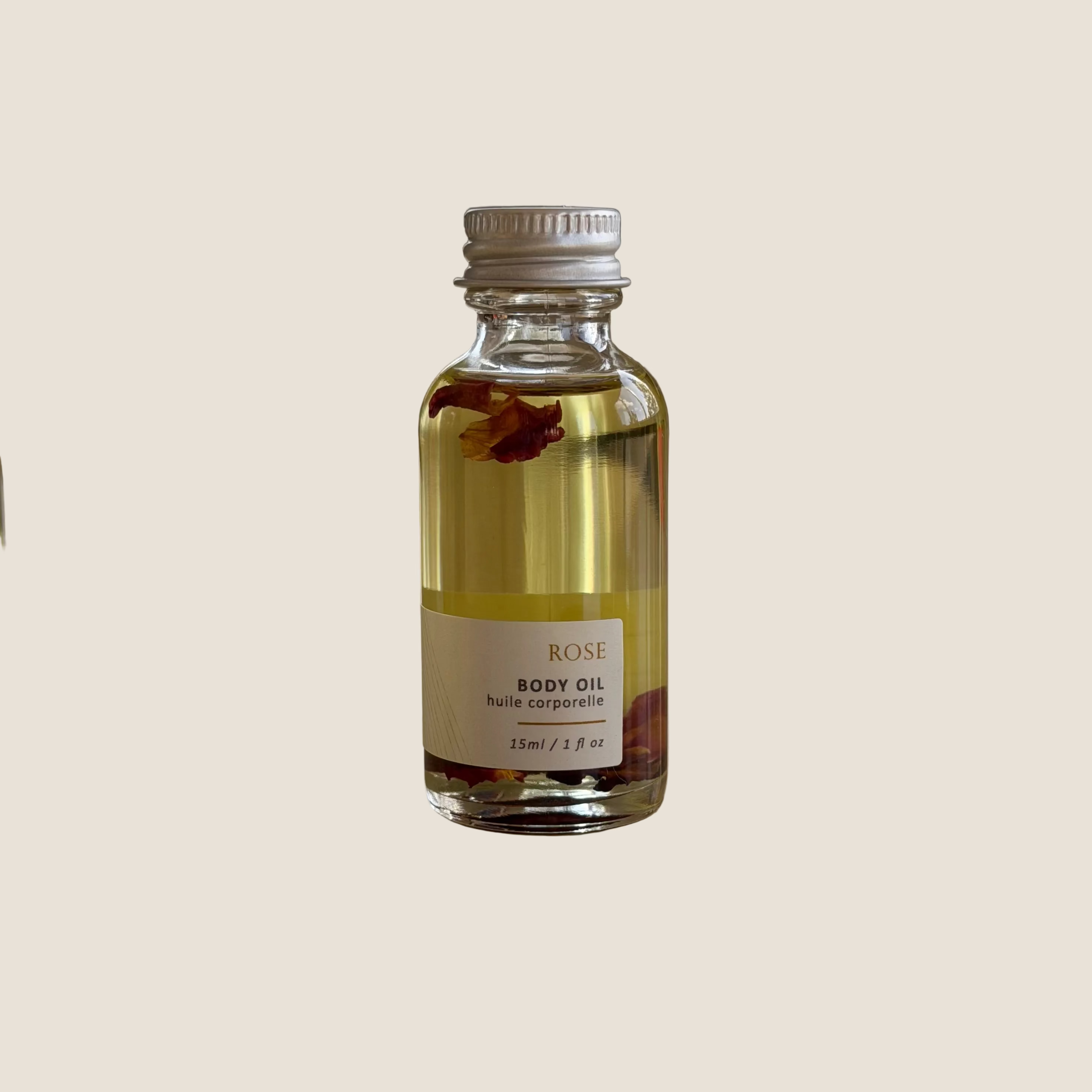 Small bottle of Sealuxe Rose body oil on a reflective surface with a blurred background