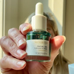 Woman in the background with Sealuxe Nourish facial oil in the foreground