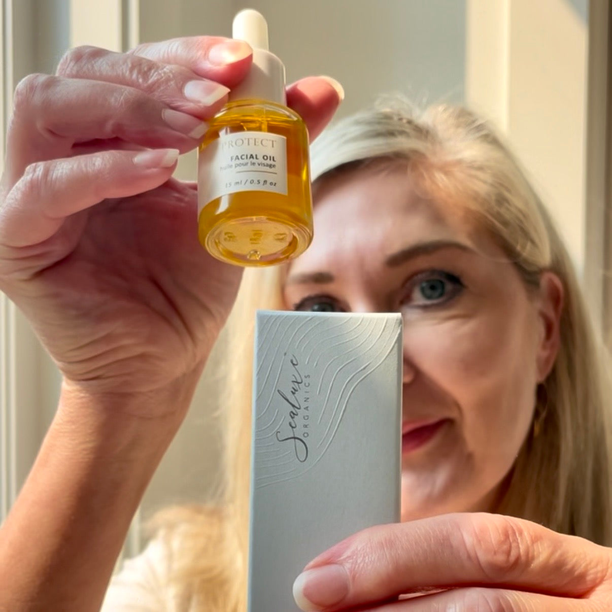 Woman in the background with Sealuxe Protect facial oil in the foreground