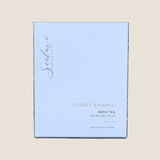 A square white box of Sealuxe Organics Forest Bathing Bath Tea. The box features elegant gold and dark gray text and subtle concentric wave patterns.
