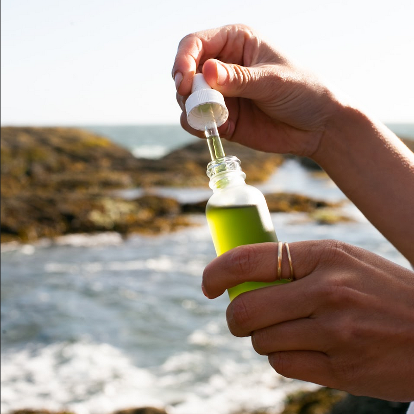 balance facial oil getting used with a dropper and ocean in the background